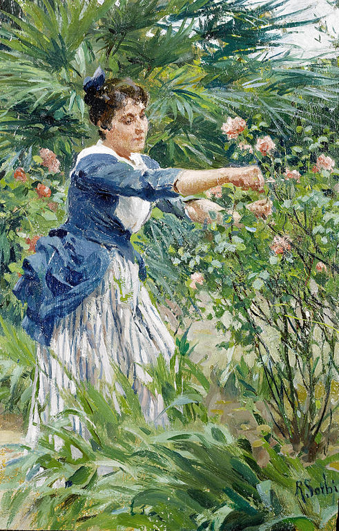 A woman pruning peach roses in a garden